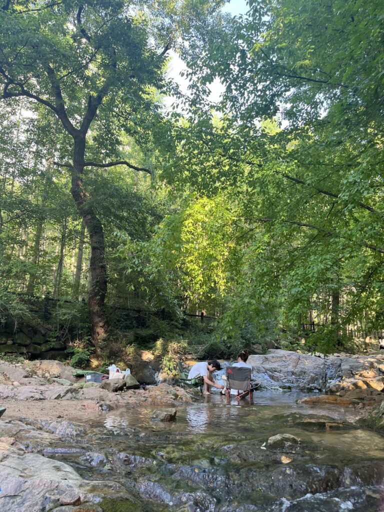 A couple sitting on camping chairs placed in the shallow water at Jingwansa Valley