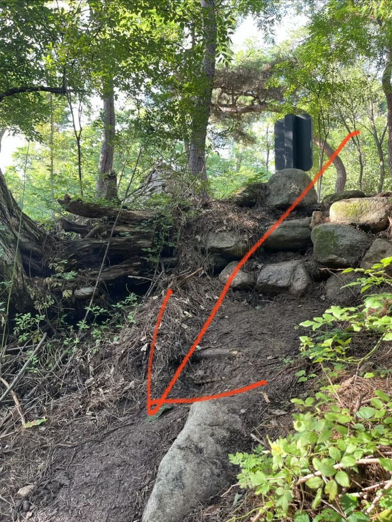 A small dirt path leading down between rocks to the stream at Jingwansa Valley