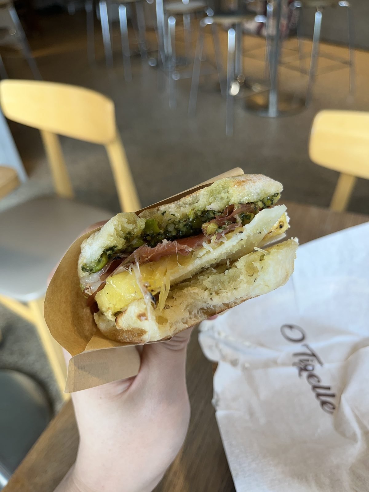 Hawaiiano tigella held in hand, filled with grilled pineapple, provolone, pistachio pesto and prosciutto