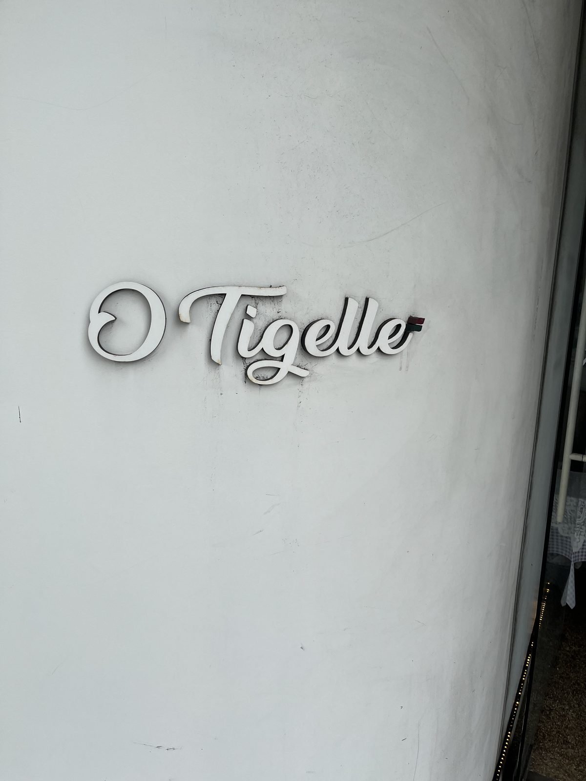 White cursive O Tigelle sign on the shop's white exterior wall in Noksapyeong, Itaewon