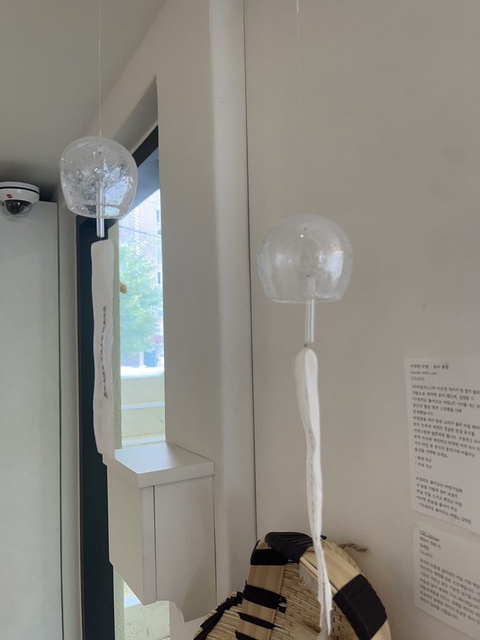 A slim white floor lamp with a round glass shade, standing by a window on the first floor.