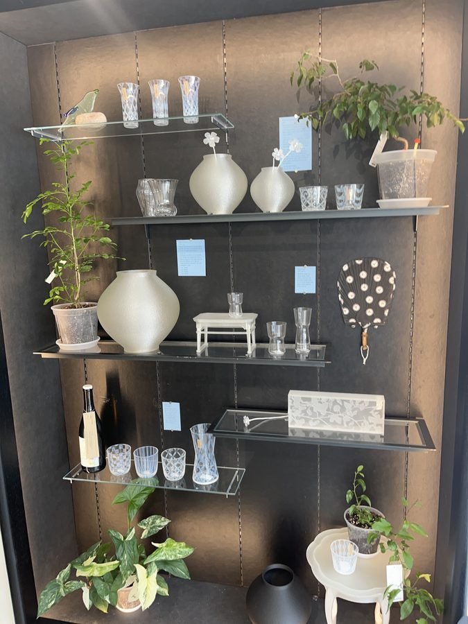 Glass shelves on the first floor holding vases, glassware and potted plants.