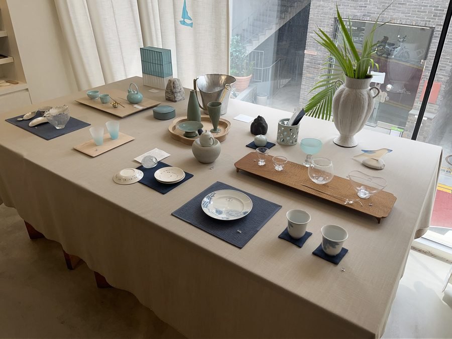 Small ceramic dishes and wooden trays arranged on a cloth-covered table.