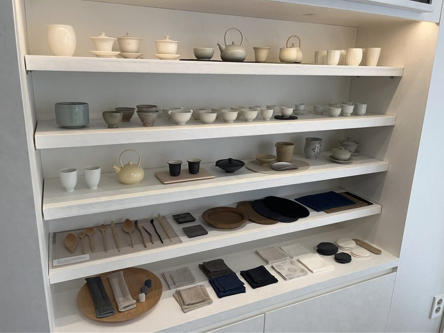 White shelves of teaware on the second floor: teapots, cups and small dishes.