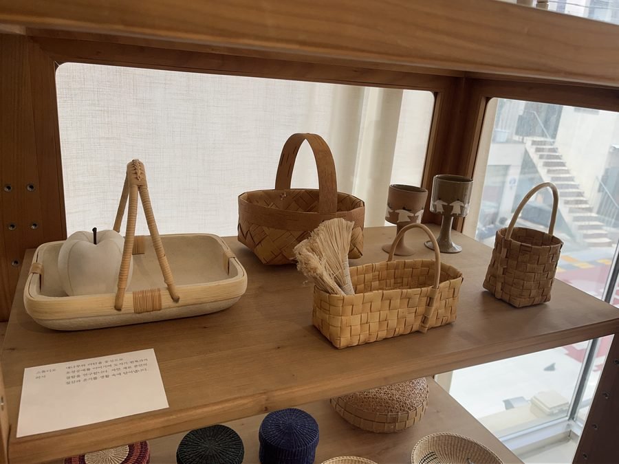 Woven baskets and a wooden bowl on a shelf beside the window.