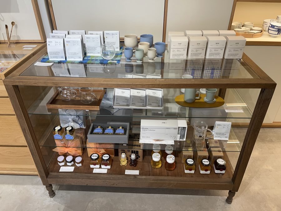 A glass display cart holding boxed goods and small bottles.