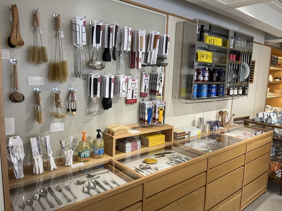 A wall of kitchen tools and brushes above a wooden drawer cabinet.