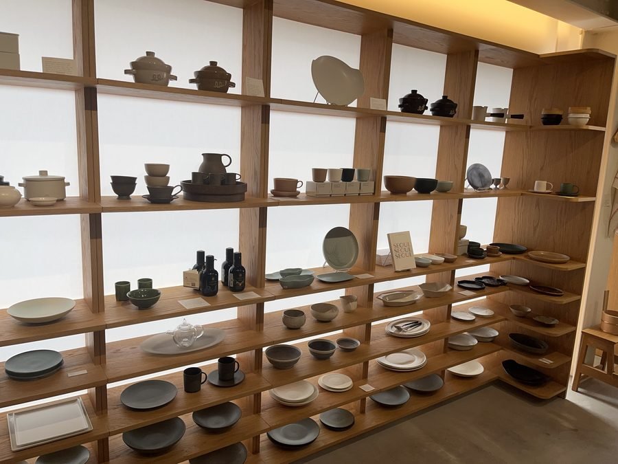 A wall of wooden shelving filled with bowls, plates and cups.