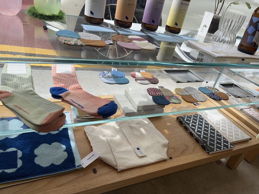 Folded textiles, socks and small ceramics in a glass display case.
