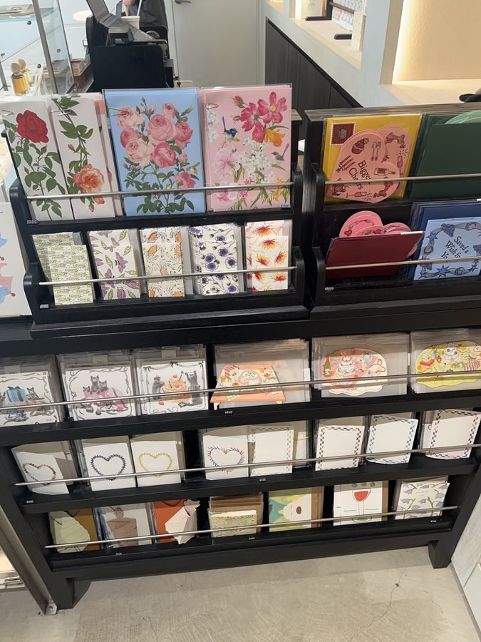 A rack of floral greeting cards with small packaged goods below.