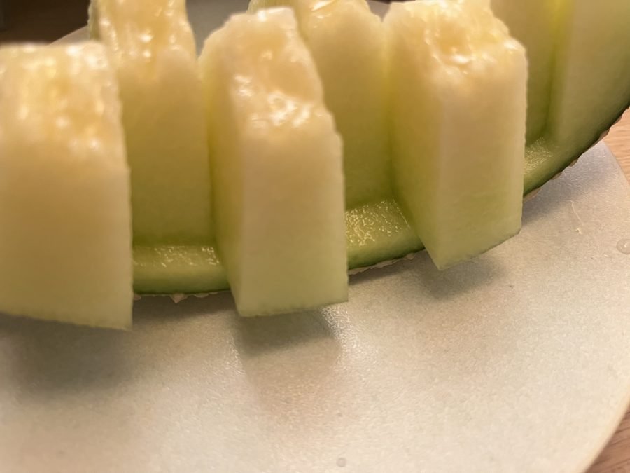 Slices of melon standing on a pale ceramic plate.