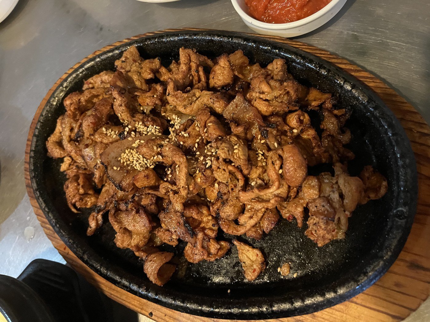 Seokswoe bulgogi arriving on a hot plate, sesame seeds on top.
