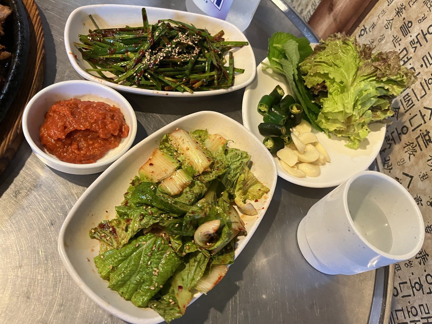 Side dishes at Jeonggane: buchu-muchim, geotjeori, lettuce and perilla leaves for ssam, and raw garlic.